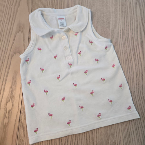 White baby romper with cherry pattern on a wooden surface